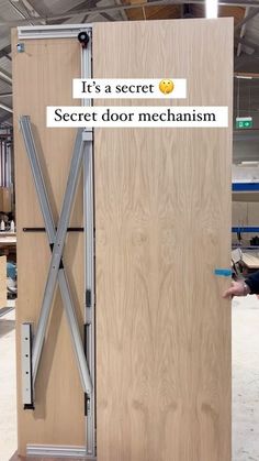 a man standing next to a wooden door that says it's a secret secret door mechanism