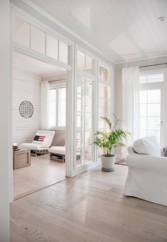 an open living room with white furniture and large windows on the side of the wall