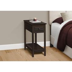 a night stand on the floor next to a bed