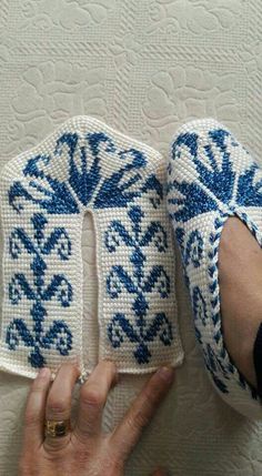 someone is holding up two crocheted shoes with blue and white designs on them