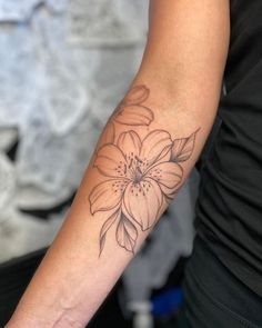 a woman's arm with a flower tattoo on the left side of her arm