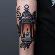 a person with a tattoo on their arm holding a lit candle in front of them