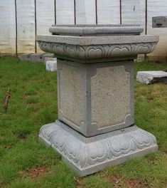 a cement urn sitting on top of a lush green field