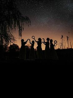 silhouettes of four women holding scissors in front of the night sky