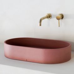 a pink oval sink sitting next to a faucet on a white counter top