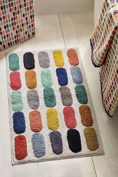 a multicolored rug on the floor in front of a chair with a blanket