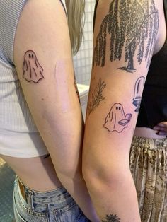 two women with matching tattoos on their arms, one has a ghost and the other has a dog