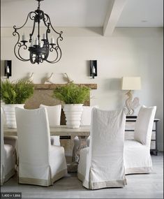 a chandelier hangs from the ceiling above a dining room table with white chairs