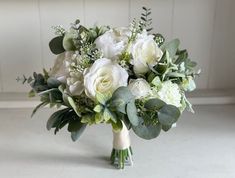 a bridal bouquet with white flowers and greenery