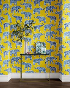 a yellow and blue wallpaper with an elephant pattern on it, next to a plant