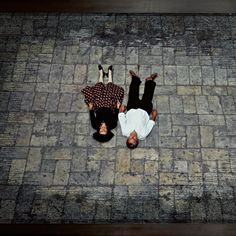 two people are laying on the ground with their hands in each other's pockets