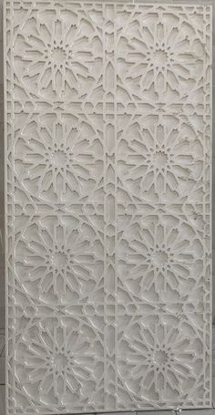 a white wall with an intricate design on the top and bottom part, in front of a tiled floor