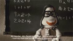 a doll is standing in front of a blackboard with writing on it and wearing glasses