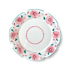 a white plate with pink flowers and green leaves on the rim is sitting on a table