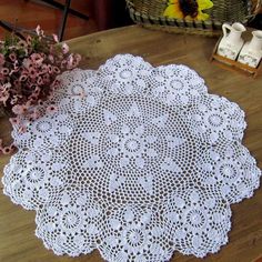 two doily sitting on top of a wooden table next to flowers and a basket