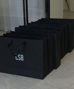 several black bags sitting on the floor in front of a window