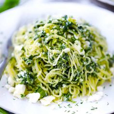 a white plate topped with pasta covered in pesto