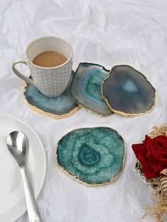 three pieces of agate glass sitting on top of a table next to a cup of coffee