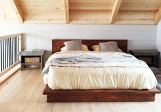 a large bed sitting in the middle of a bedroom next to a wooden floor and ceiling