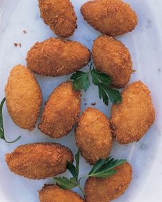 some fried food on a white plate with parsley sprigs in the middle