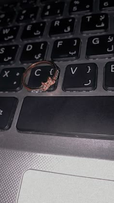 a ring is sitting on the keyboard of a laptop that has it's keys missing