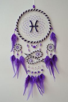 a purple and white dream catcher hanging on a wall