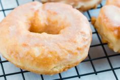 three glazed donuts sitting on top of a cooling rack next to another doughnut