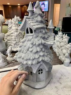 a person is making a miniature house out of clay and fake snow on the table