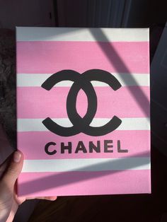 a person holding up a pink and white card with the word chanel on it