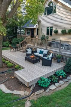 a deck with chairs and couches in front of a large house next to a tree