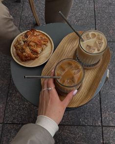 two people sitting at a table with drinks and pastries on the trays in front of them