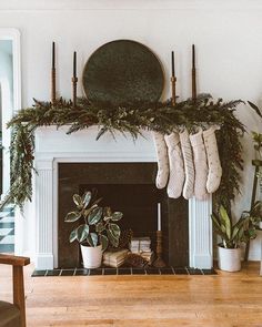 a fireplace with stockings hanging from the mantle and potted plants in front of it