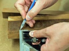 a person is using a pencil to draw something on a piece of wood with a hole in it