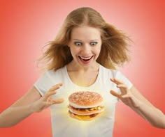 a woman holding a hamburger in front of her face with both hands and eyes open