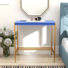 a blue table with flowers and a mirror on it next to a bed in a room