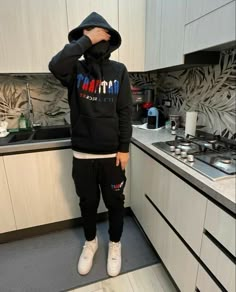 a person standing in a kitchen wearing a black hoodie and sweatpants with the word miami printed on it