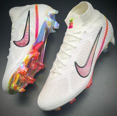 a pair of white nike soccer cleats with multicolored stripes on the soles