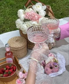 a table topped with wine glasses and strawberries next to a basket filled with flowers