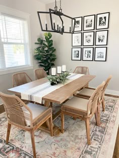 a dining room table with chairs and pictures on the wall behind it, along with a rug