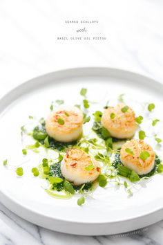 three scallops on a white plate with green garnish