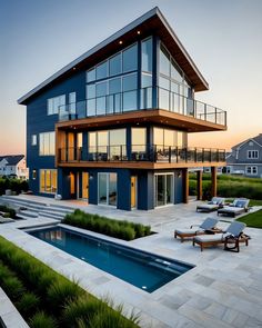 a house with a pool in front of it and some lounge chairs on the lawn