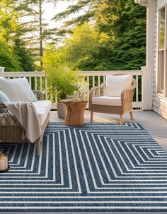 a porch with two chairs and a rug on the floor next to an outdoor table