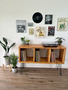 an old record player sits on top of a wooden shelf next to some plants and records