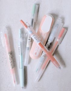 several pens and markers are lined up on the table next to an eraser, toothbrush, and pill bottle