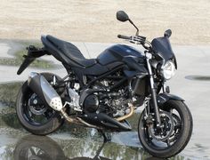 a black motorcycle parked on the side of a road next to puddles of water