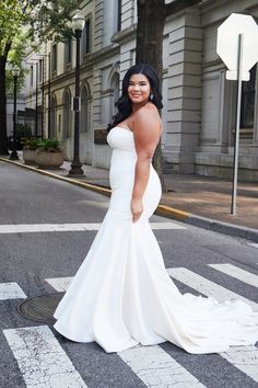 a woman in a white dress standing on the street