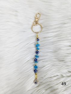 a key chain with evil eye beads and a gold ring on top of white fur