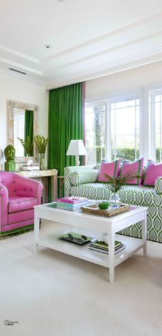 a living room with green curtains and pink accents on the couches, coffee table