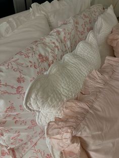 an unmade bed with pink and white sheets