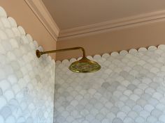 a shower head and arm in a bathroom with white bubbles on the wall behind it